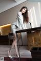 A woman in a white suit leaning on a desk.