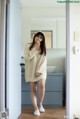 A woman standing in front of a mirror in a bathroom.