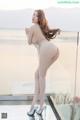 A woman in a silver bodysuit posing on a balcony.