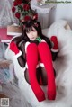 A woman in a santa outfit sitting on a white chair.