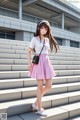 A girl in a pink skirt and white shirt is standing on some steps.