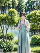 A woman in a blue dress standing in a park.