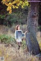 A woman standing next to a tree in a field.